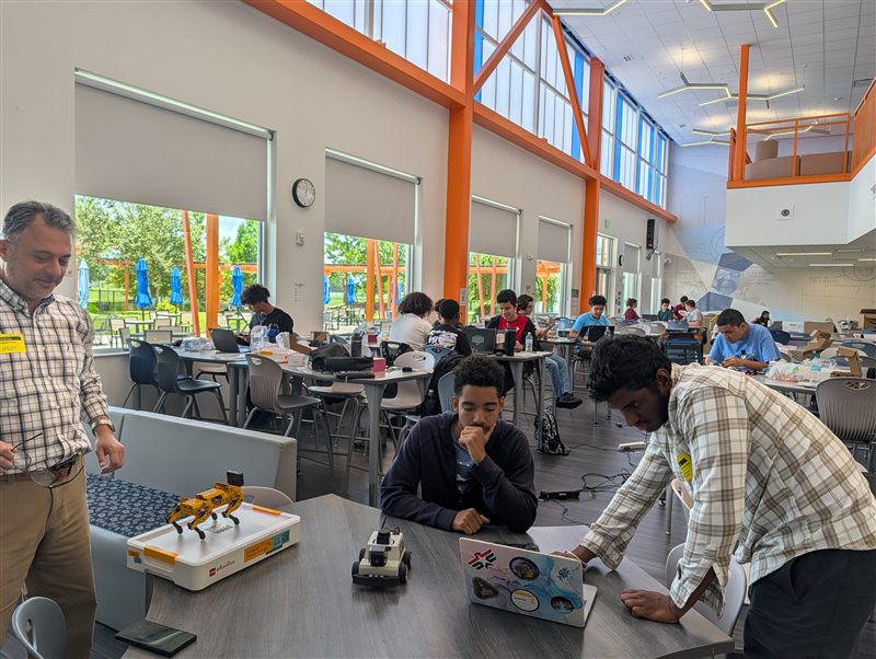 Students prototype and program AI-guided robots on laptops.