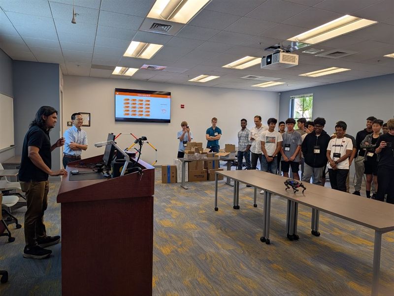 Dr. Prabhu demos an AI-guided quadruped robot to students at the podium.